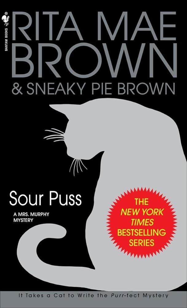 Used paperback book cover of Sour Puss: A Mrs Murphy Mystery by Rita Mae Brown, showing the book title, author name, and cover artwork in very good condition
